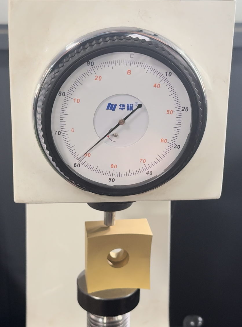 Full inspection photograph of a TiN-coated cutter insert beneath the hardness tester